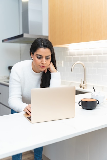 Mujer joven en busca de una receta en su computadora