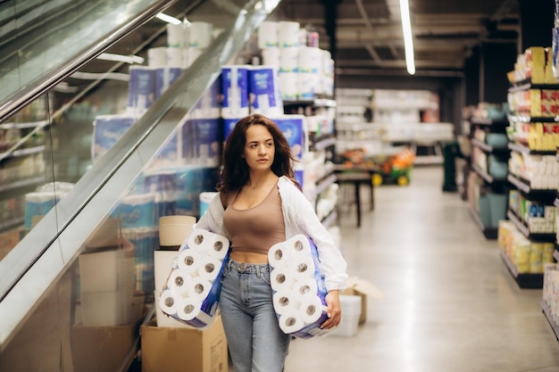 Mujer joven buscando comprar un paquete de papel higiénico en el supermercado Foto de alta calidad