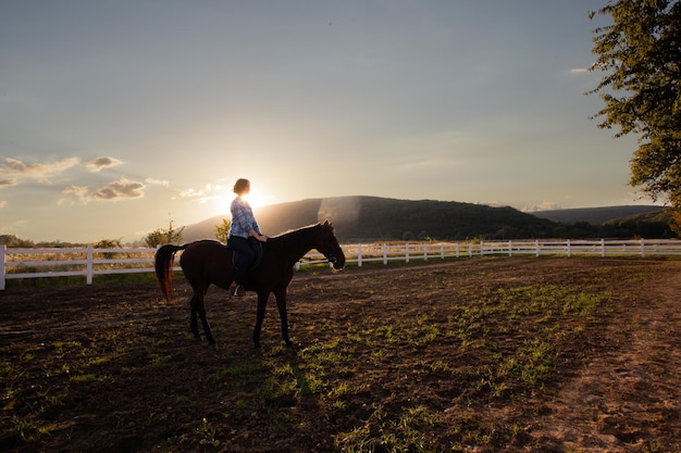 Una mujer joven a caballo mira la puesta de sol