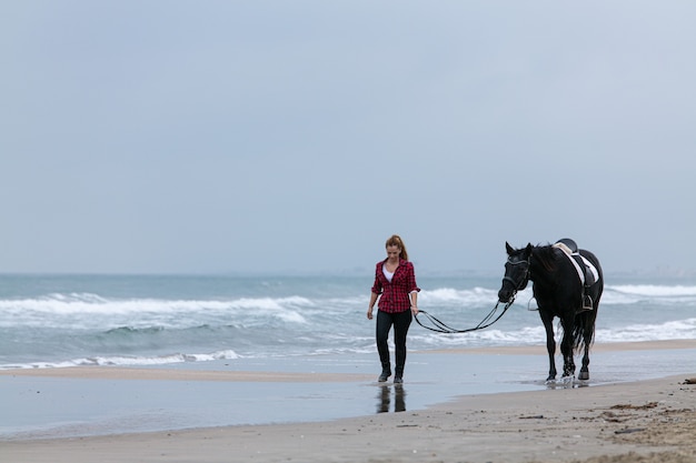 Mujer joven a caballo en la playa en un día nublado
