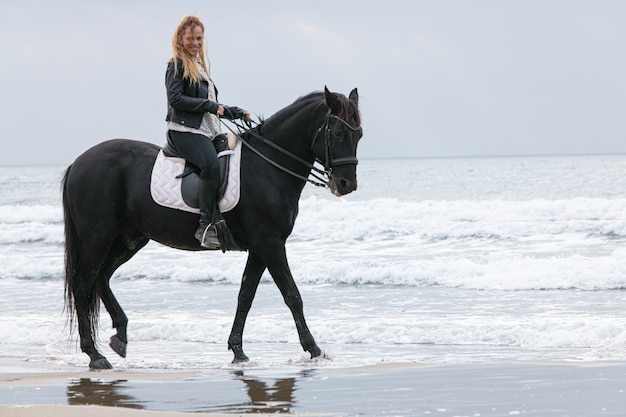 Mujer joven, en un caballo, en la playa