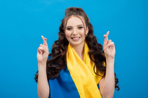 Foto mujer joven con cabello castaño oscuro sobre fondo azul claro con bandera azul y amarilla de ucrania