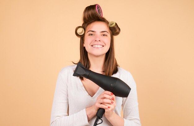 Mujer joven con el cabello liso secando el cabello con un secador de cabello profesional