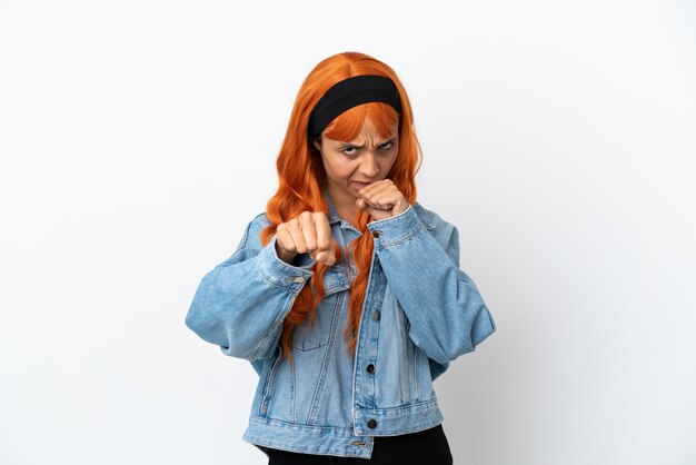 Mujer joven con cabello naranja aislado sobre fondo blanco con gesto de lucha