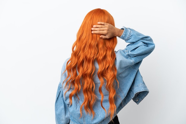 Mujer joven con cabello naranja aislado sobre fondo blanco en posición de espalda y pensando