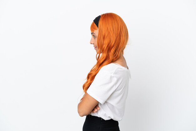 Mujer joven con cabello naranja aislado sobre fondo blanco en posición lateral