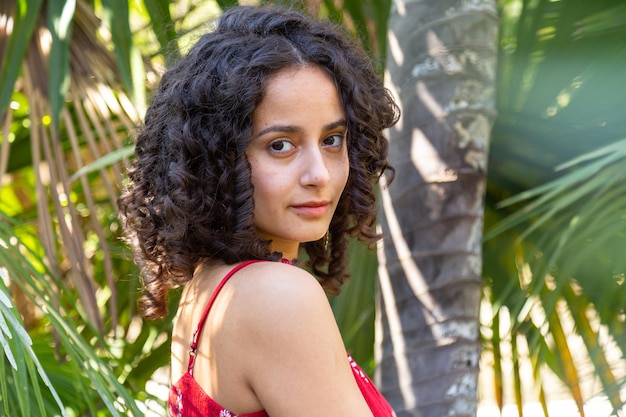 Mujer joven con cabello rizado disfrutando en un parque paradisíaco