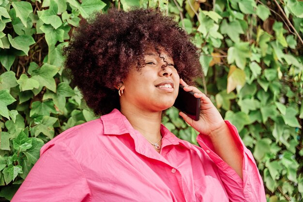 Mujer joven con cabello rizado usando su teléfono inteligente retrato de mujer afroamericana hablando por teléfono