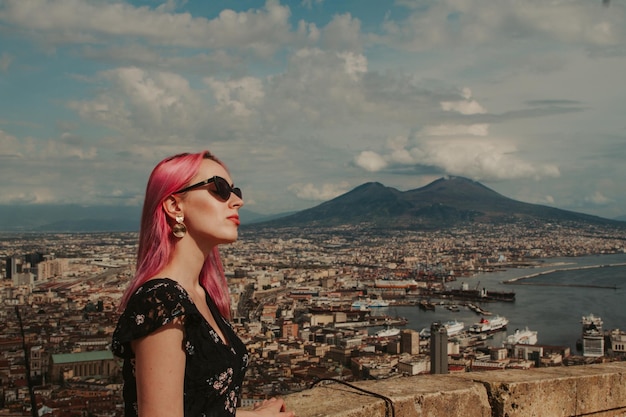 Una mujer joven con cabello rosa mira el volcán Vesubio