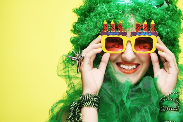 Mujer joven con cabello verde y gafas de carnaval.