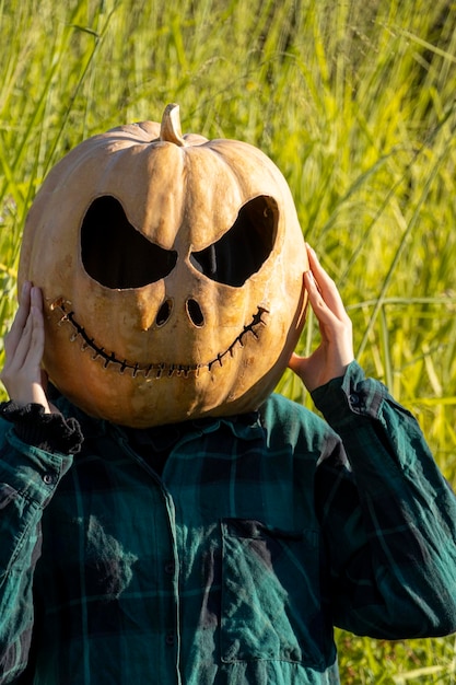Mujer joven con cabeza de calabaza después de cortarla y ponerle cara de halloween