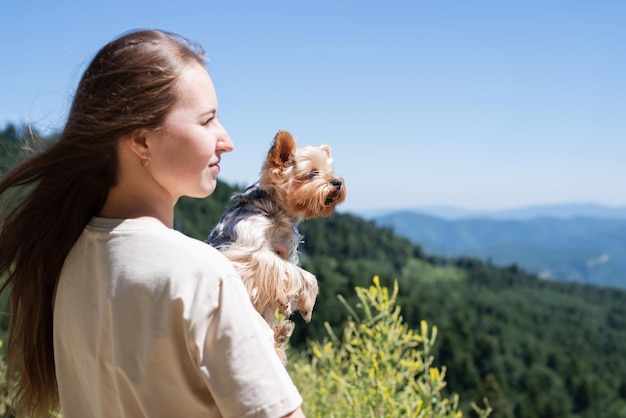 Mujer joven con cachorro de perro pequeño yorkshire terrier senderismo en las montañas