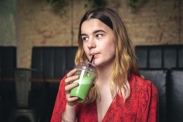 Una mujer joven en un café bebe un café con leche verde