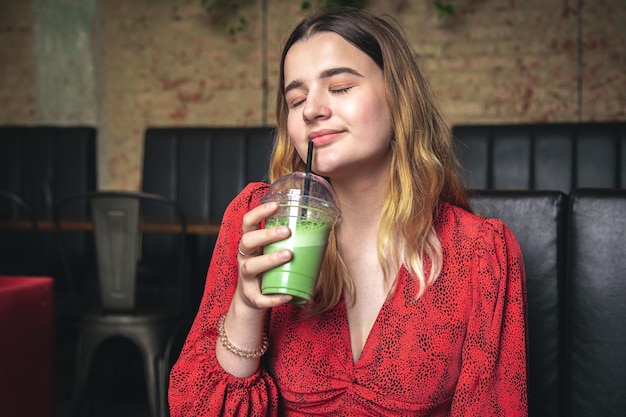 Una mujer joven en un café bebe un café con leche verde