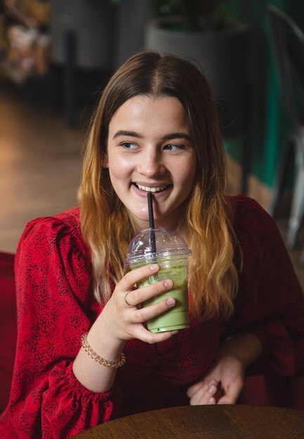 Una mujer joven en un café bebe un café con leche verde