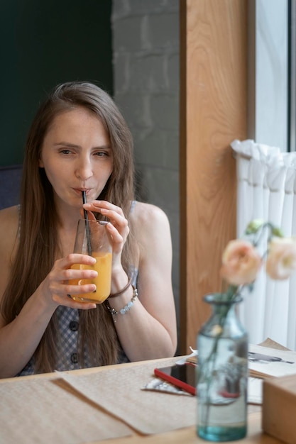 mujer joven, en, café, bebidas, cóctel, jugo, bebida, por, paja, niña, se relaja, en la mesa, en, café, marco vertical