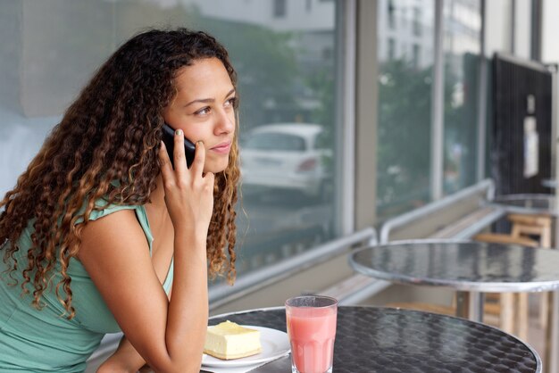 Mujer joven en café haciendo una llamada telefónica