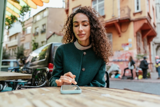 Mujer joven en un café leyendo un mensaje de su teléfono móvil