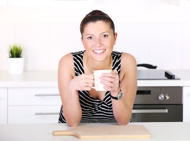 mujer joven con café matutino en la cocina