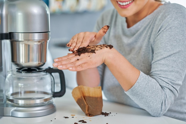 Mujer joven con café molido lo usa para pelar