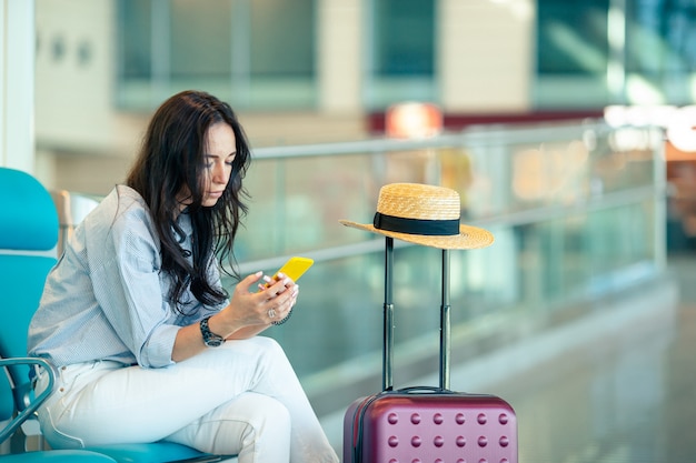 Mujer joven con café en un salón del aeropuerto esperando el avión de vuelo