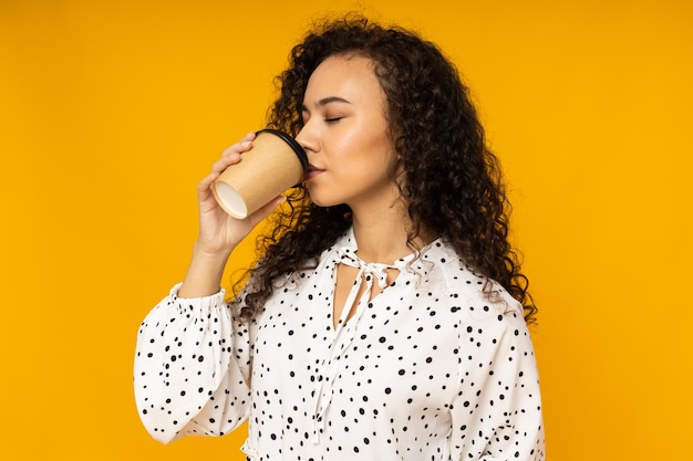 Mujer joven con café sobre fondo amarillo