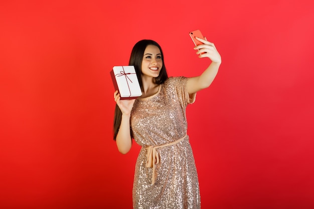 Mujer joven con caja de regalo haciendo selfie en su teléfono