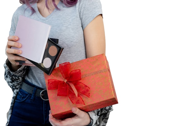 Mujer joven con caja de regalo con paletas de maquillaje, tiro del estudio sobre un fondo blanco. Espacio vacio