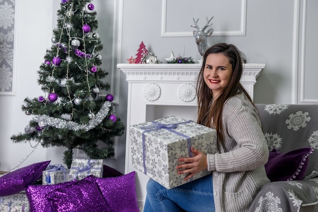 Mujer joven con caja de regalo posando en estudio de navidad