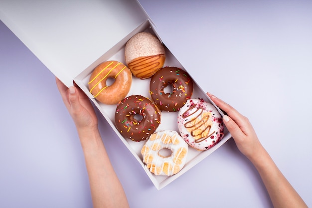 Mujer joven con caja de rosquillas dulces - fotografía colorida - vista superior