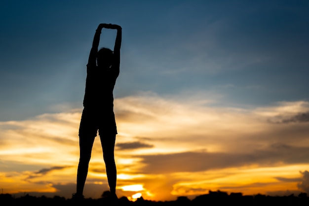 Mujer joven calentando al aire libre en el parque