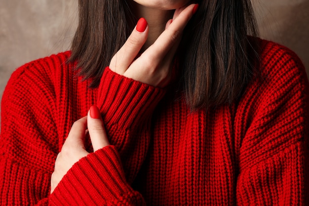 Mujer joven en cálido suéter rojo sobre marrón