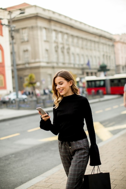 Mujer joven en la calle con teléfono móvil y escuchar música