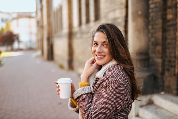 Mujer joven en la calle tomando café.