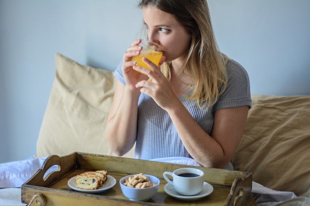 Mujer joven en la cama desayunando