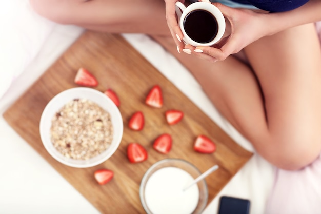 mujer joven, en cama, con, desayuno, y, smartphone