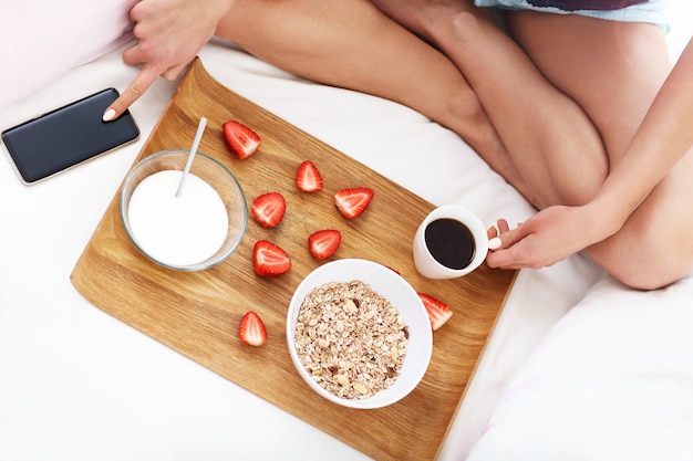 mujer joven, en cama, con, desayuno, y, smartphone