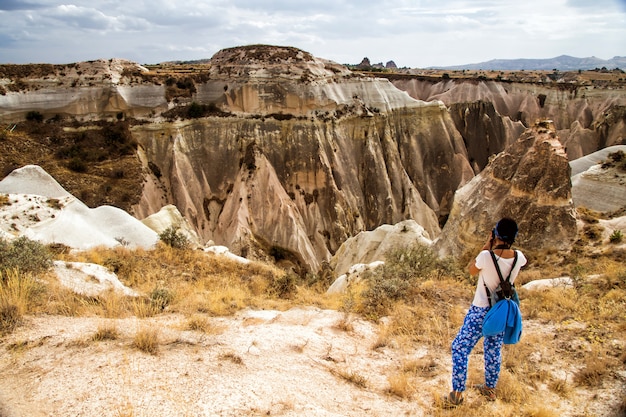 Mujer joven con cámara y mochila tomando foto en Capadocia, Turquía.