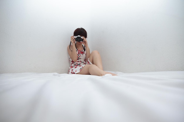 Mujer joven con una cámara retro en la cama