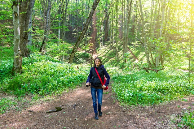 Una mujer joven camina en el bosque en un día de primavera