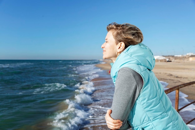 Foto una mujer joven camina a lo largo de la playa de arena en la temporada de invierno en un día soleado vacaciones en el complejo en la temporada baja