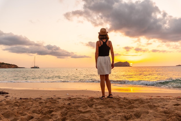 Mujer joven caminando al atardecer en la playa de Cala Comte en la isla de Ibiza Balearic