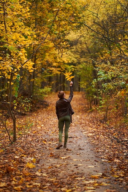 Mujer joven caminando en el bosque de otoño