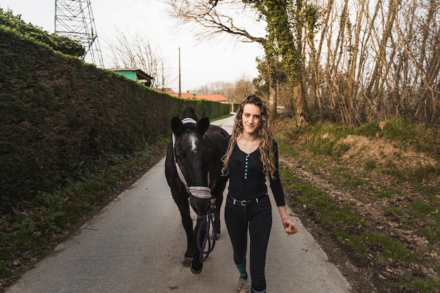 Mujer joven caminando con un caballo por el centro ecuestre