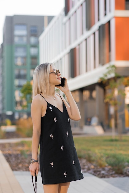 Mujer joven caminando por las calles de la ciudad mientras habla en su teléfono