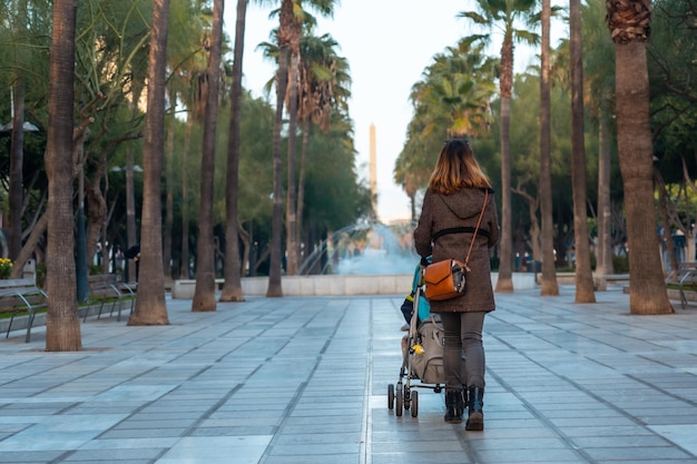 Una mujer joven caminando junto a las palmeras en la calle Belén de la Rambla de Almería, Andalucía. España. Costa del sol en el mar mediterráneo