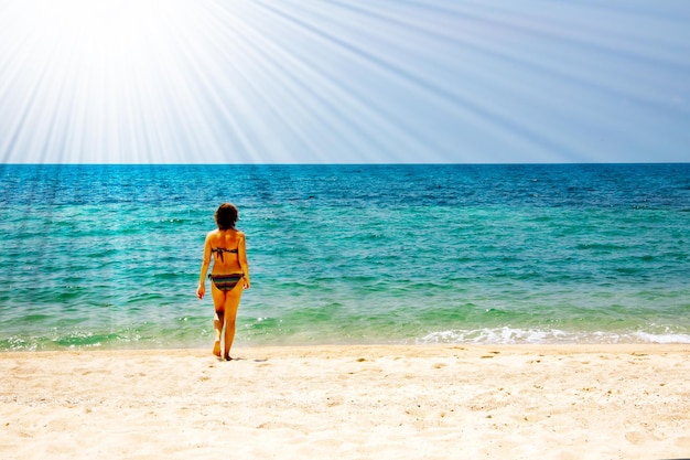 Mujer joven caminando para nadar en el mar