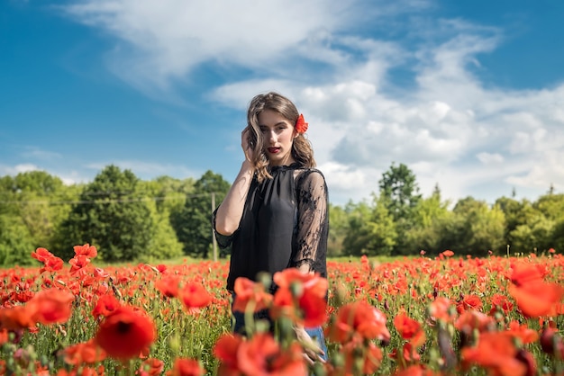 Mujer joven caminando sobre el campo de amapolas rojas, horario de verano. Disfruta de la libertad en la naturaleza