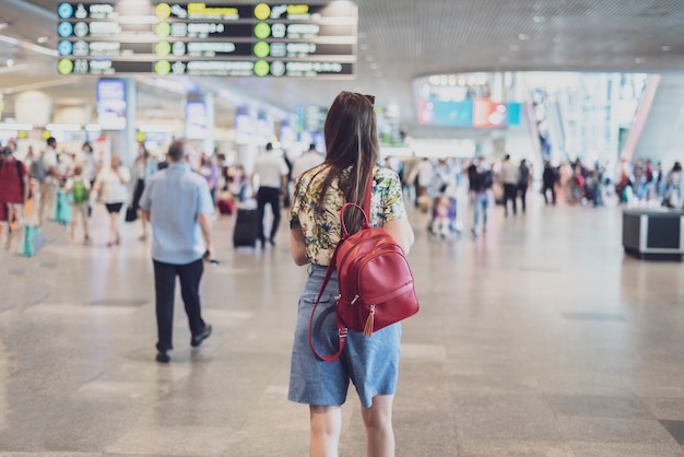 Una mujer joven caminando en la terminal del aeropuerto para el vuelo del avión