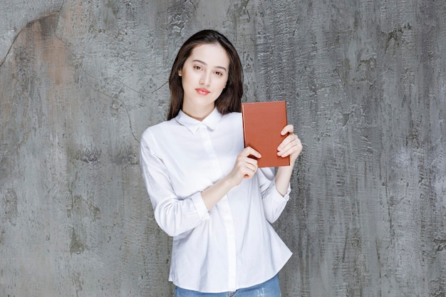 Mujer joven con camisa blanca que muestra el libro. foto de alta calidad